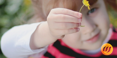 Ein Kindergartenkind zeigt eine gelbe Blume 