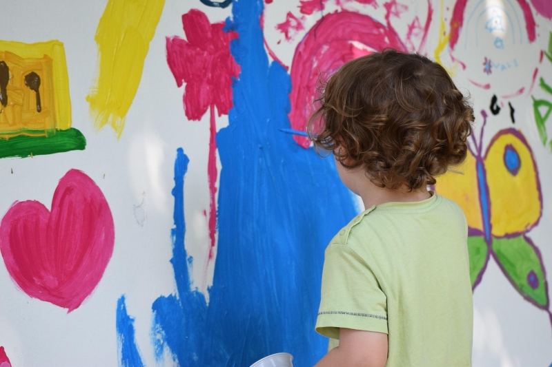 Kind malt ein großes Bild an der Wand