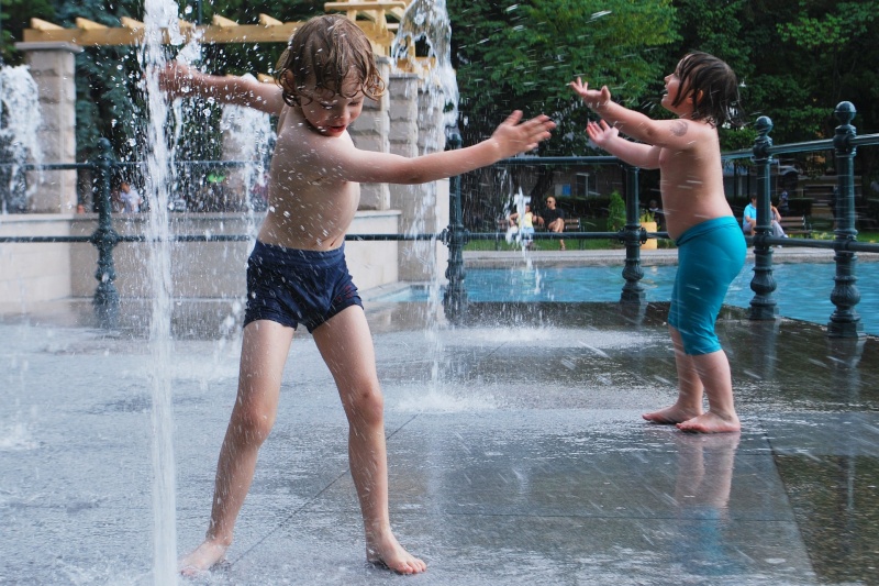 Kinder spielen an einem Wasserbrunnen